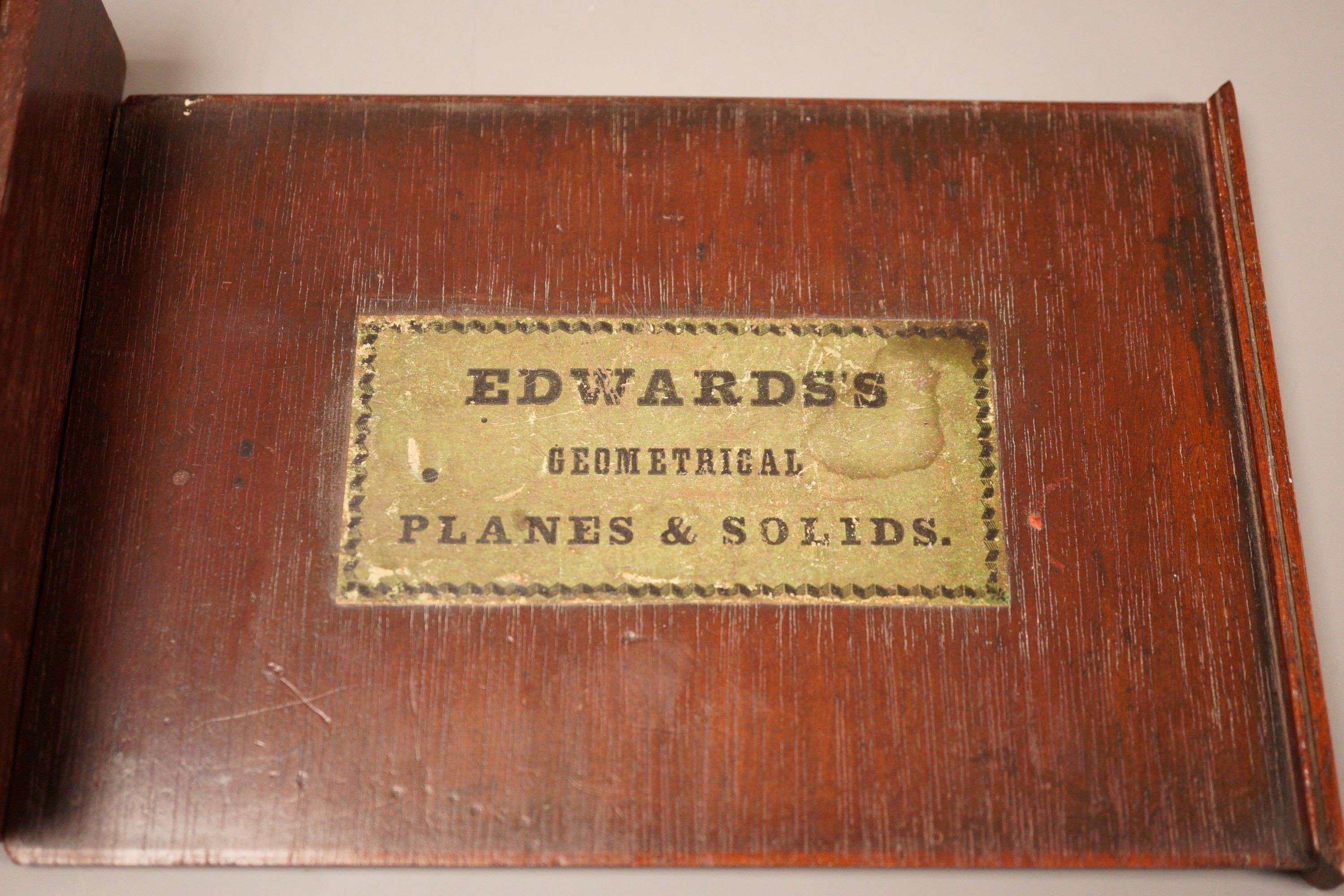A mahogany cased set, Edwards Geometrical Planes and Solids': 19th century educational carved wooden geometry instructional set, with paper label to cover